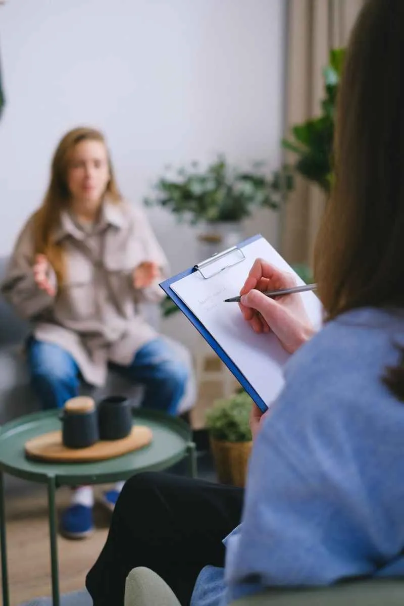 crop psychologist writing on clipboard during psychotherapy session